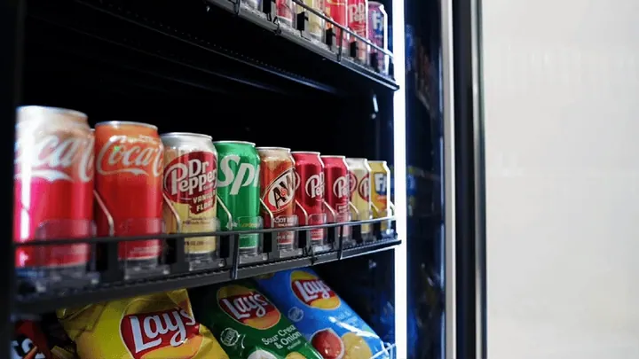 A customer selects drinks and snacks from an open smart cooler
