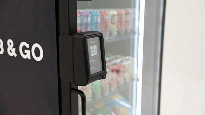 A customer taps a phone on a smart cooler payment reader